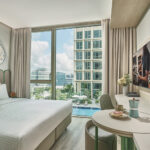 Citadines hotel room with comfortable seating, large windows, and urban views.