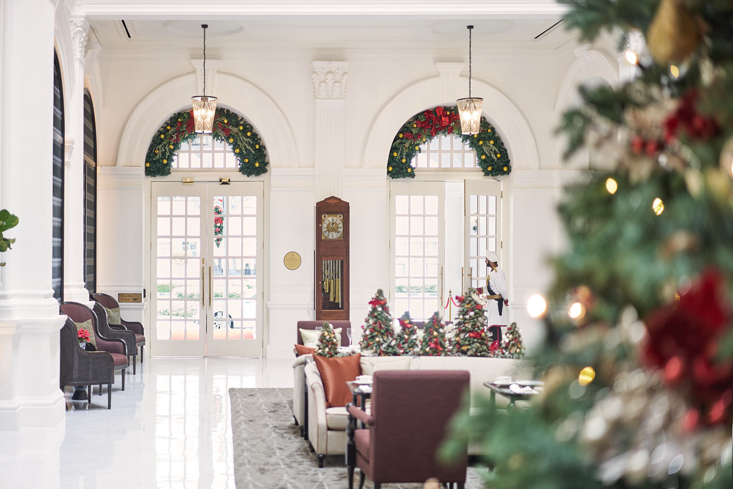 Warm and inviting lobby entrance at Raffles Hotel Singapore, showcasing antique furniture and high ceilings.