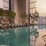 Crystal-clear waters of Oasia Downtown's swimming pool reflecting the sunset.
