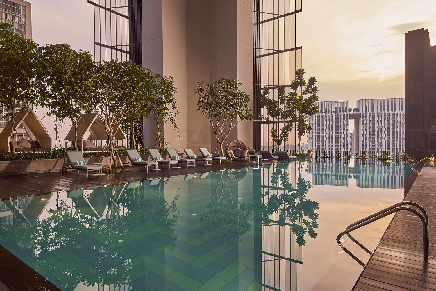 Crystal-clear waters of Oasia Downtown's swimming pool reflecting the sunset.