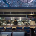 Upscale dining ambiance in restaurant with modern open kitchen and soft lighting.