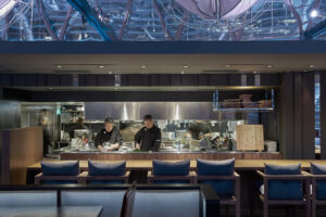 Upscale dining ambiance in restaurant with modern open kitchen and soft lighting.
