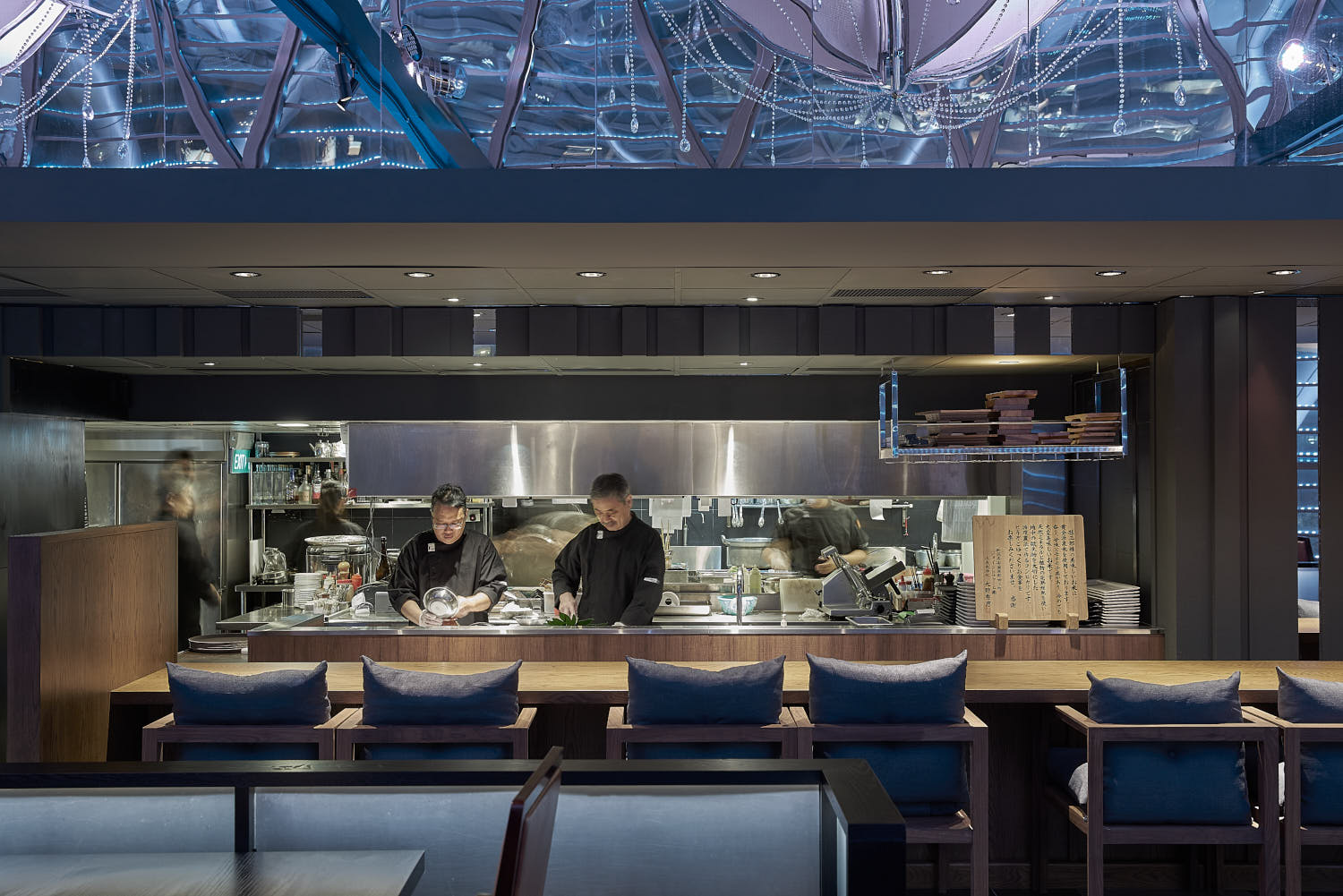 Upscale dining ambiance in restaurant with modern open kitchen and soft lighting.