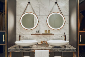 Spacious luxury bathroom at The Barracks Hotel, featuring marble countertops and gold accents.