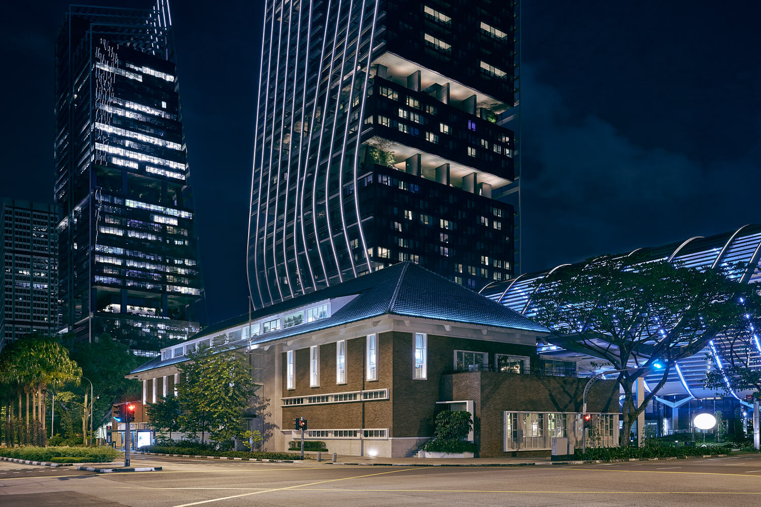 Illuminated facade of The NCO Club at JW Marriott Singapore, showcasing modern design and elegant lighting at night.
