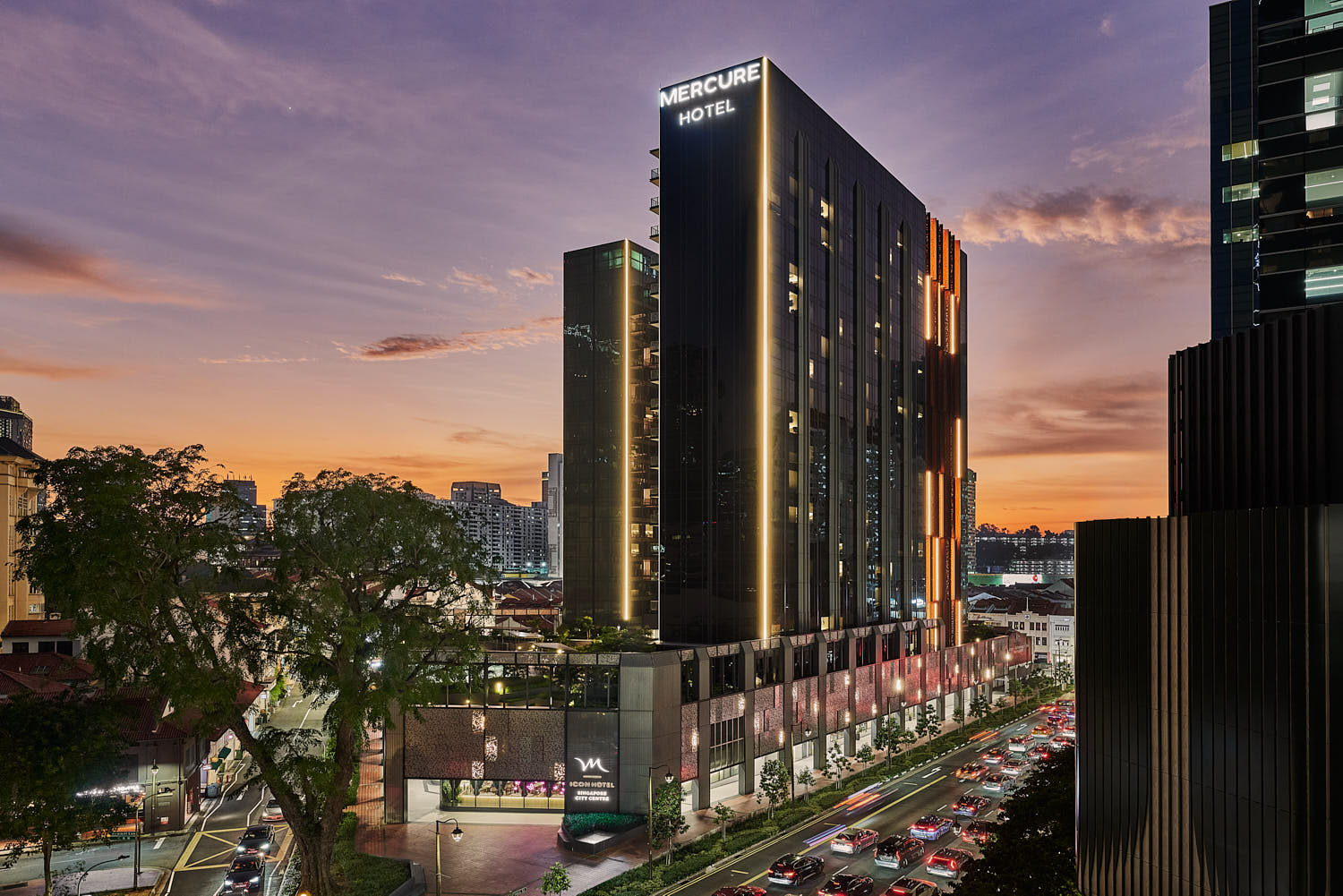 Mercure ICON hotel exterior showcasing contemporary architecture against a stunning sunset backdrop.