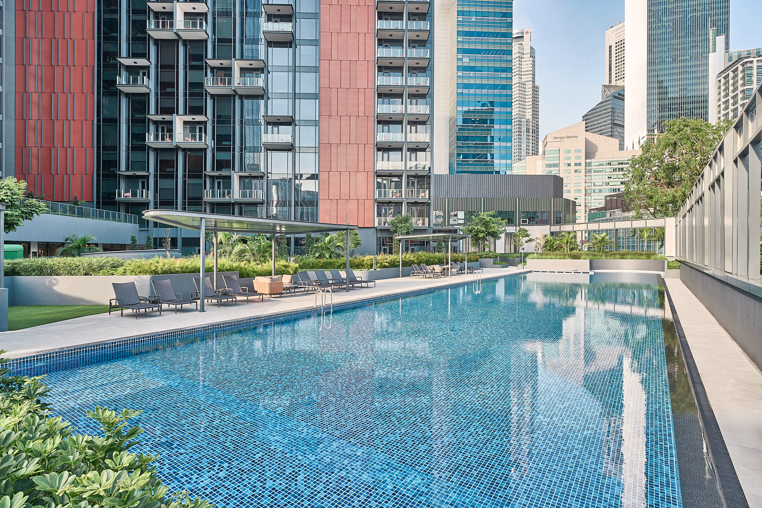 Spacious poolside at Mercure with modern lounge chairs and a tranquil atmosphere.