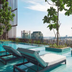 Crystal-clear waters of Oasia Downtown's swimming pool reflecting the sunset.