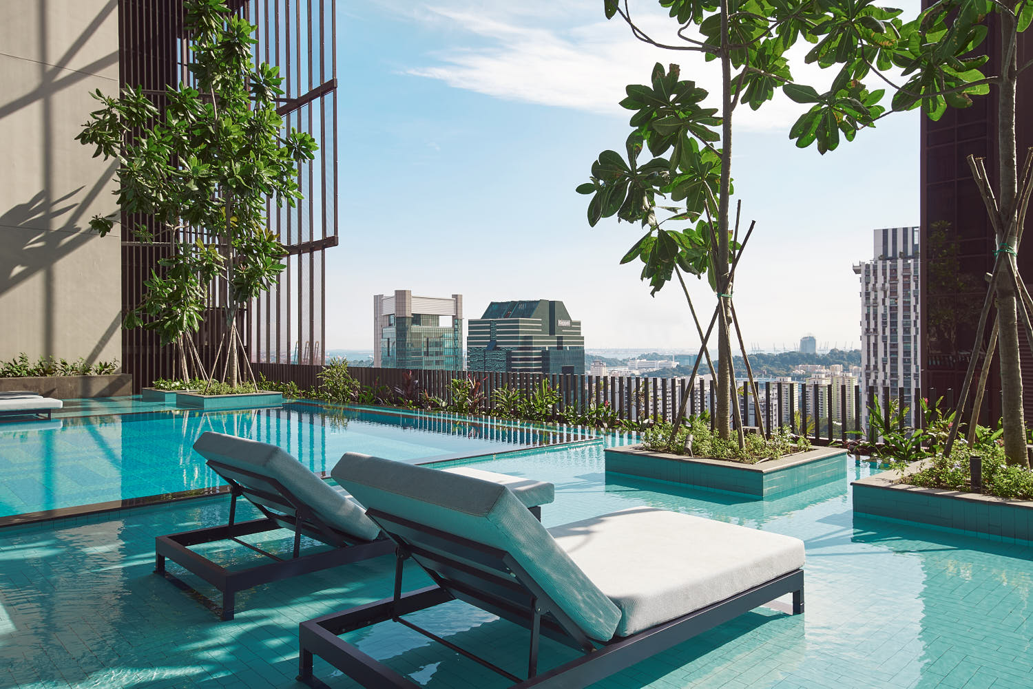 Crystal-clear waters of Oasia Downtown's swimming pool reflecting the sunset.