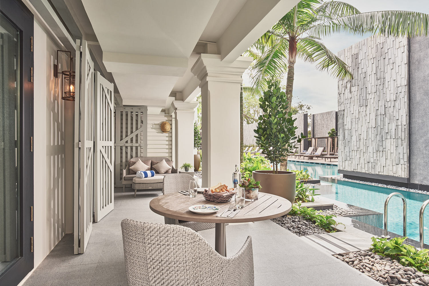 Room foyer at The Barracks Sentosa, featuring a cozy breakfast setup with a view of the serene pool.
