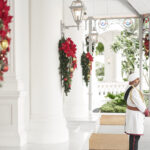 Doorman in uniform standing at the entrance driveway of Raffles Hotel Singapore, with classic architecture in the background.