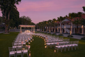 Grand outdoor sunset wedding setup at The Barracks Hotel Singapore, featuring a lavish floral arch and spacious garden.