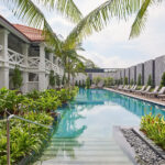 Serene outdoor swimming pool at The Barracks Hotel Sentosa, nestled among lush greenery and tropical plants.