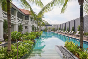 Serene outdoor swimming pool at The Barracks Hotel Sentosa, nestled among lush greenery and tropical plants.