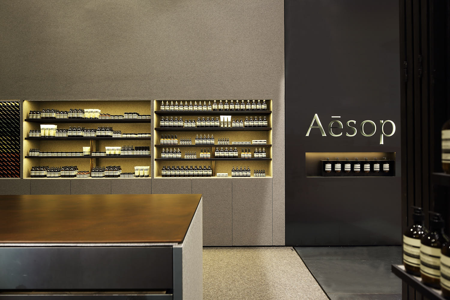 Minimal product display wall with metal shelving and suede-lined surface.