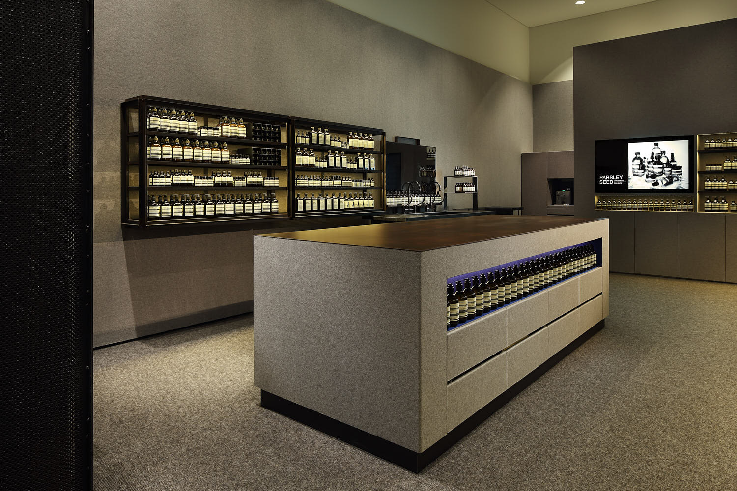 Carpeted floors meet raw metal textures in Aesop’s retail interior.
