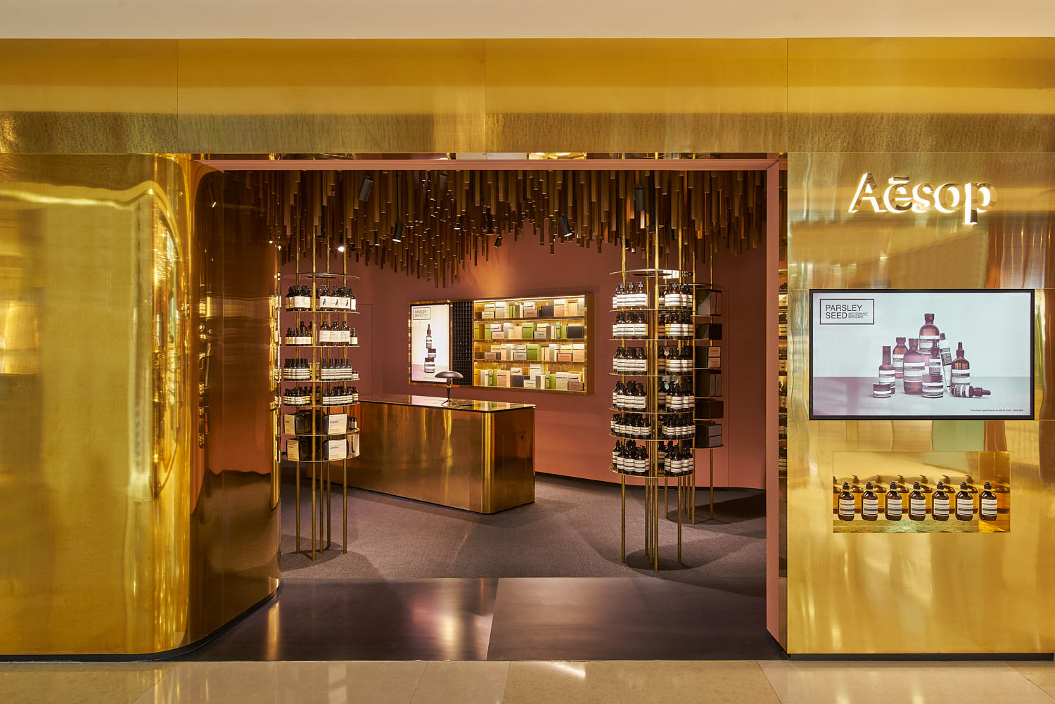 Detail of Aesop’s pillared shelving system paired with wood and brass textures.