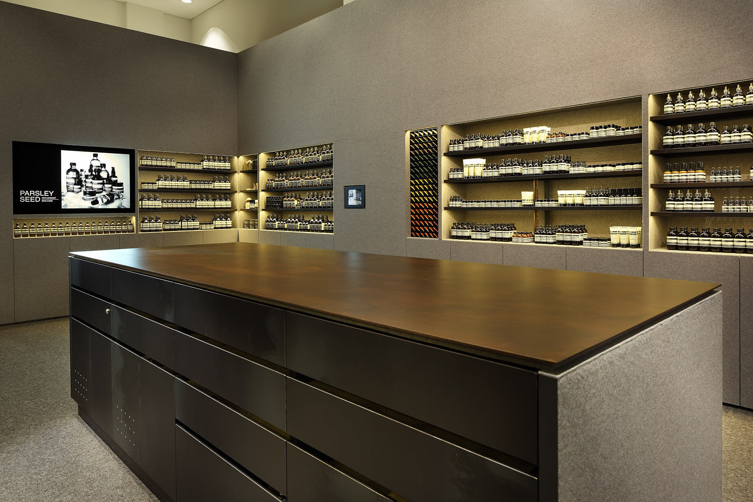 Warm industrial design with carpet flooring and suede wall finishes at Aesop.