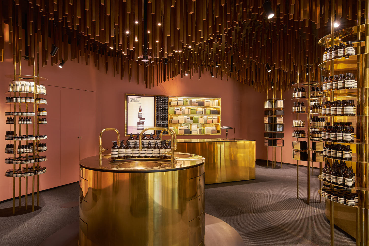 Aesop store interior featuring a wooden overhang ceiling and central sink installation.