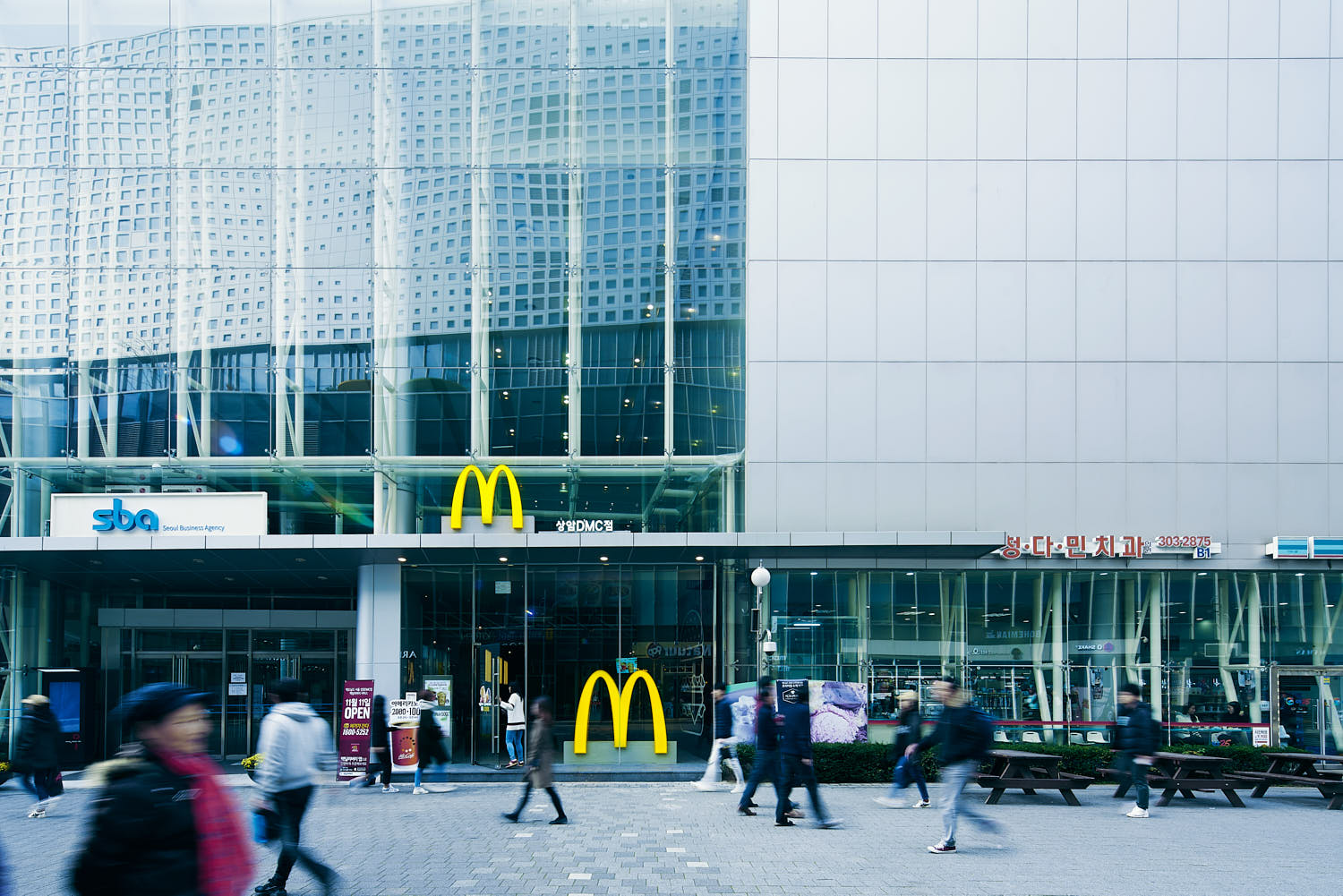 Street view of McDonald’s storefront in Korea set against a busy city backdrop.