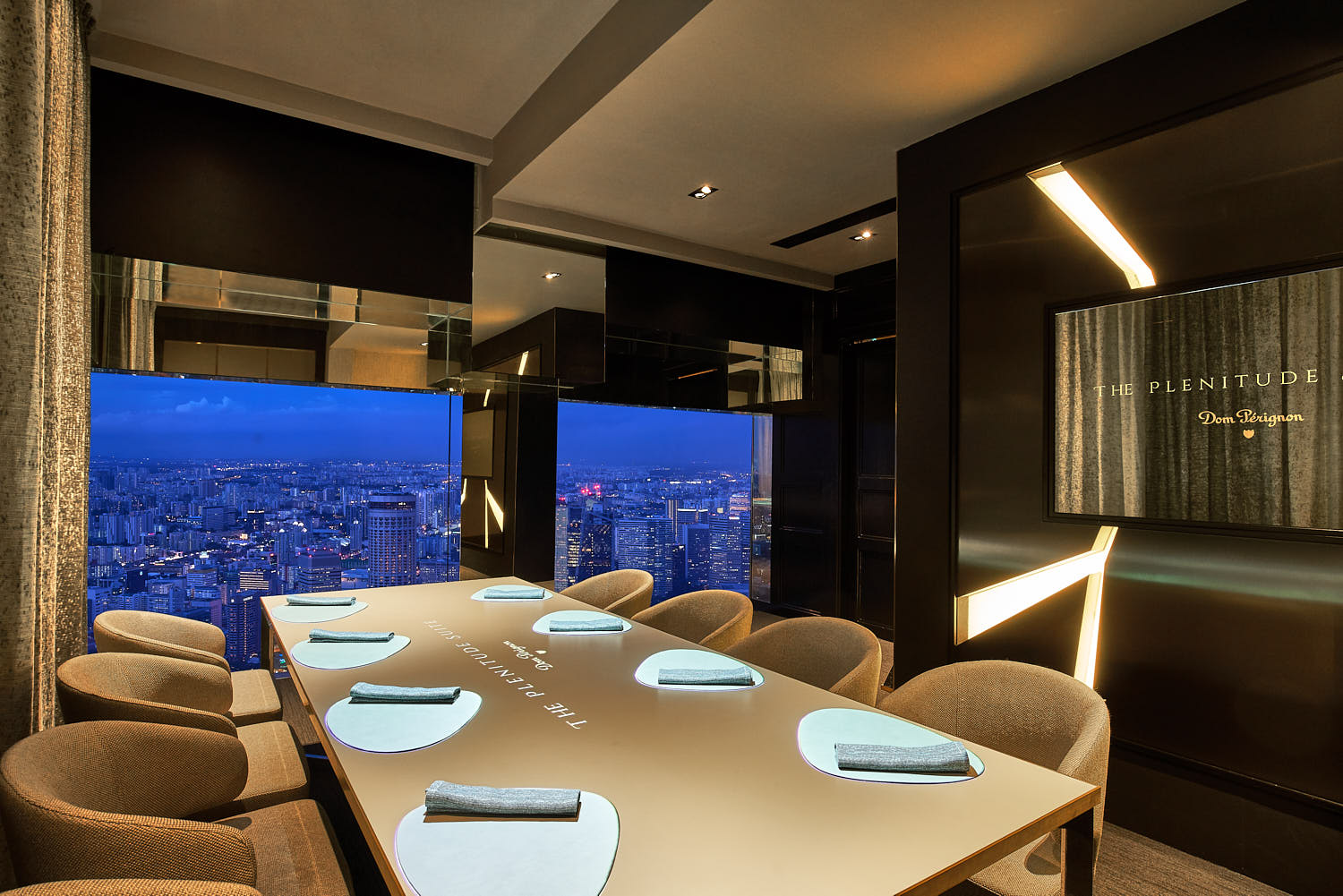 Windows frame the glowing cityscape in an intimate, refined setting.